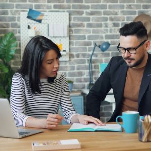 What exactly are buyer-led sales behaviours? two people in. a meeting looking at a notebook with a laptop open