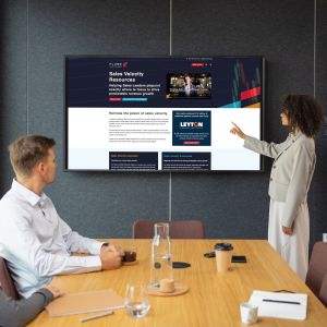 Flume sales velocity scorecards on screen in a meeting of sales people around a desk looking at a big screen.
